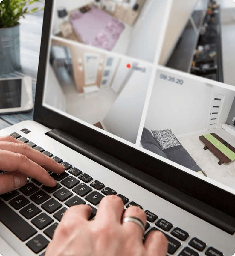 A person typing on a laptop with a photo of a room in the background.